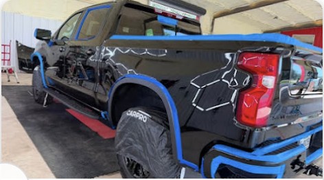Black pickup truck masked and prepared for paint correction inside the shop